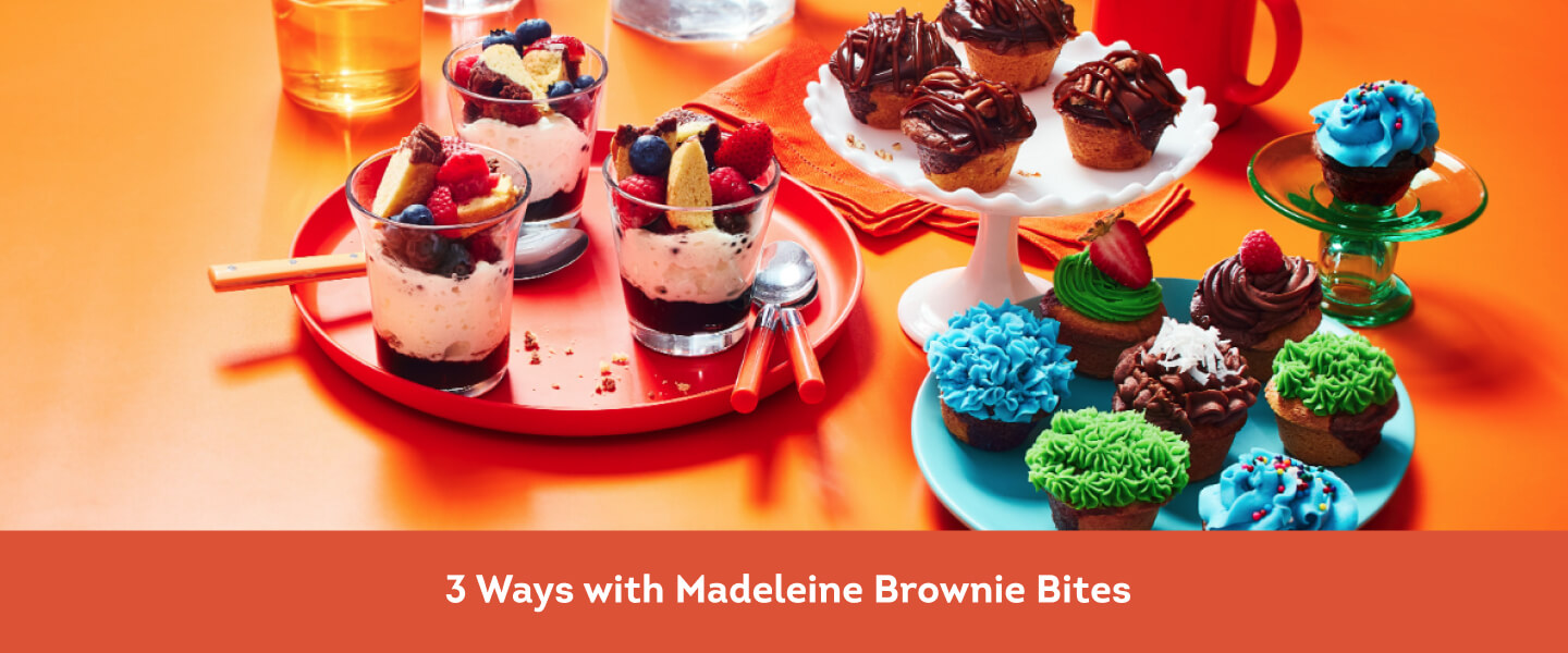 Brownie Madeleine trifle cups, caramel brownie Madeleine, and mini brownie Madeleine cupcakes on an orange backdrop