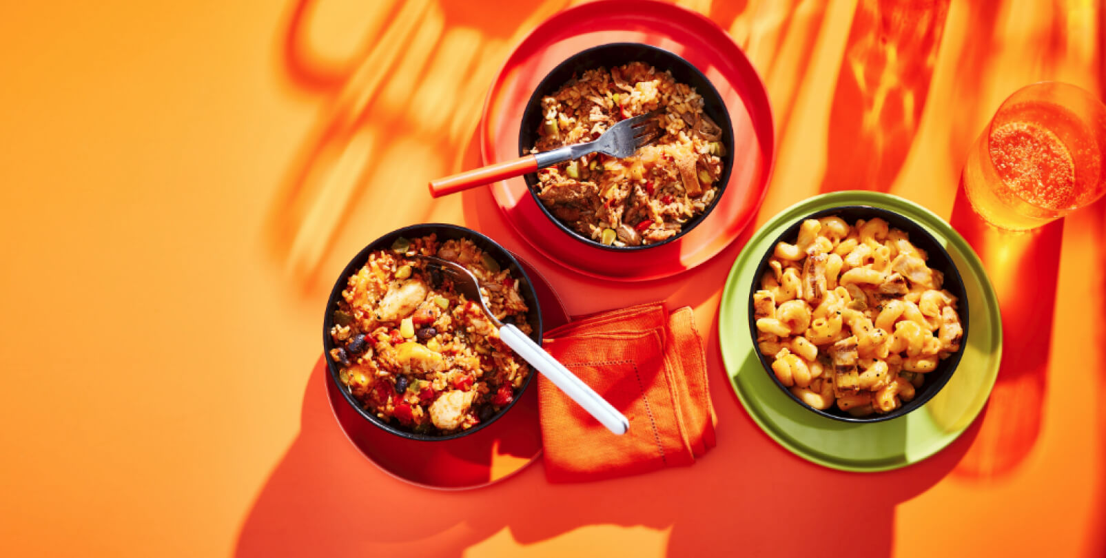 Mac n cheese and burrito bowls on an orange backdrop