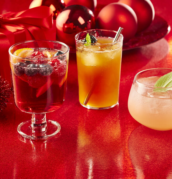 Sangria pétillante, thé glacé festif et spritz d'agrumes hivernal sur fond rouge.