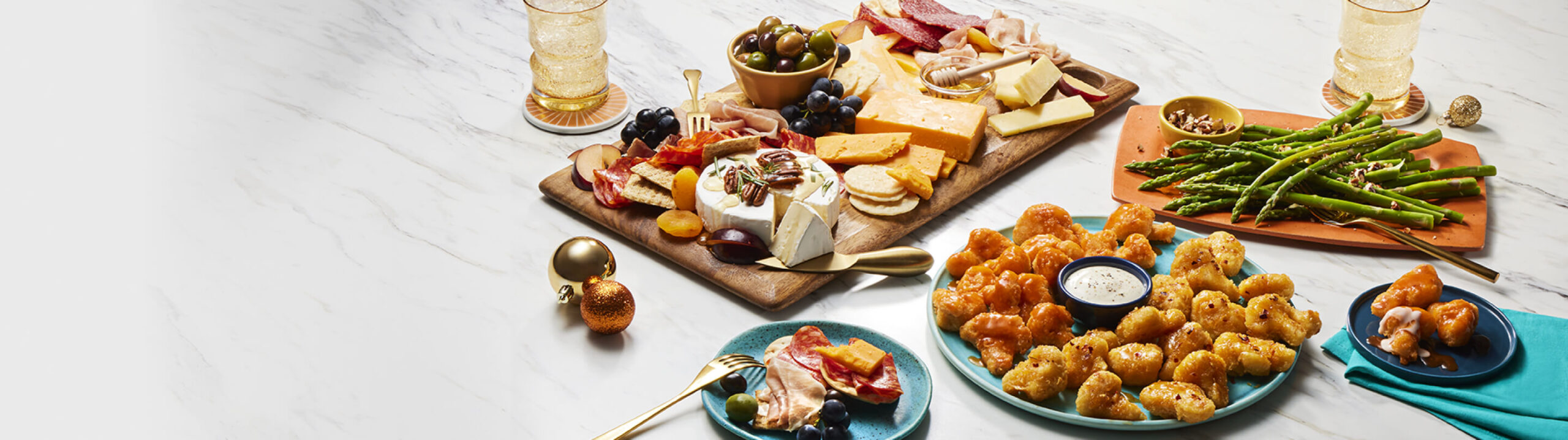 Charcutirie board, cauliflower bites, and asparagus on marble counter